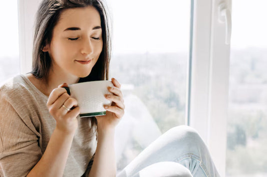 Woman drinking a warm mug by a window