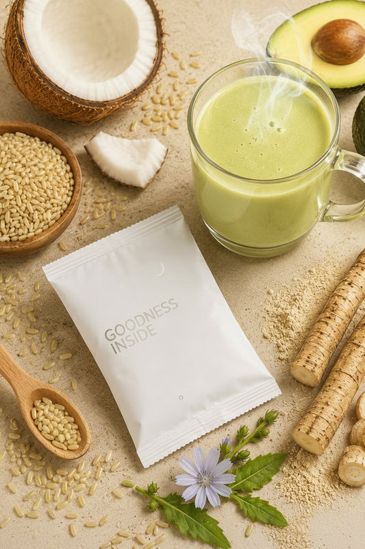 A white pouch labeled 'GOODNESS INSIDE' surrounded by green smoothie ingredients including a glass of pale green drink, avocado, coconut, seeds, and root vegetables on a beige textured surface.